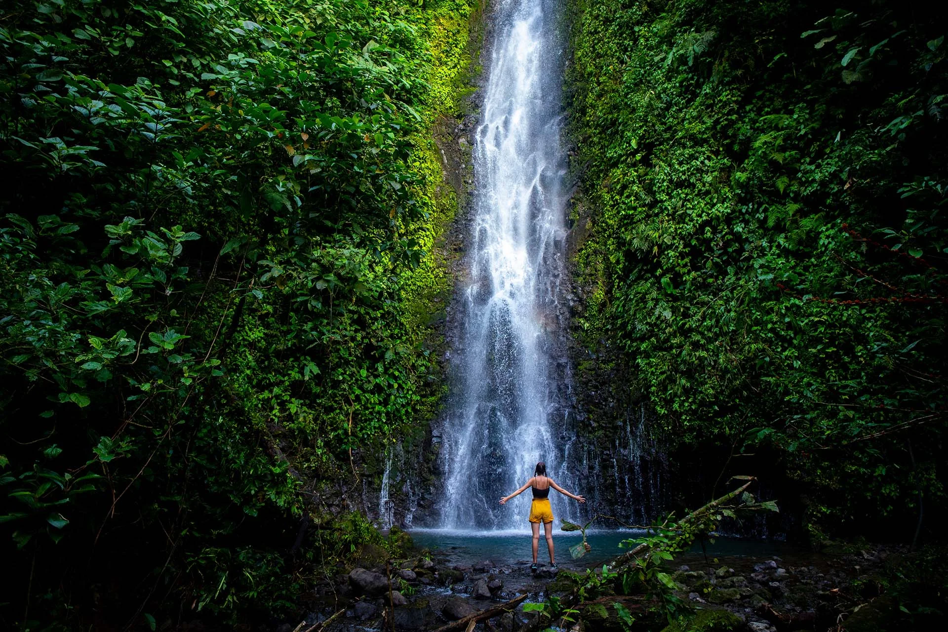 a woman standing in front of a waterfall