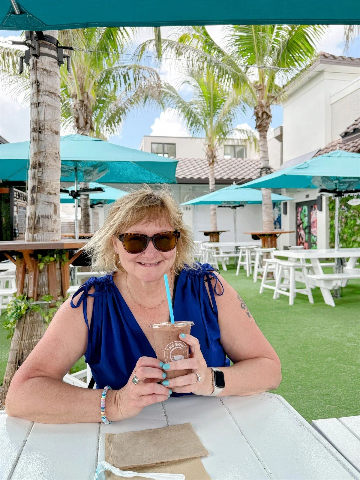 woman in sunglasses on a solo trip drinking a smoothie